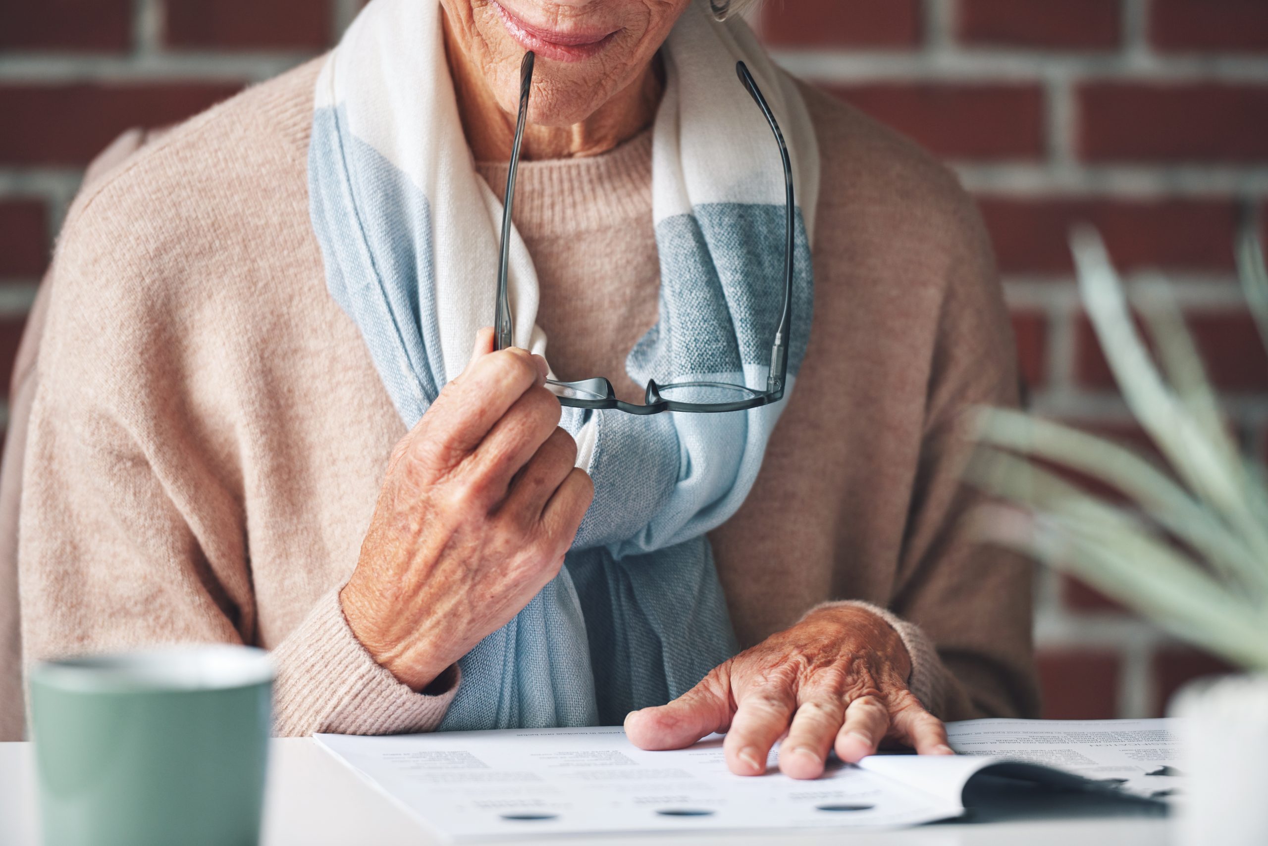 Mature woman reading financial insurance documents at home.A senior woman reading financial paperwo.